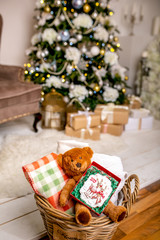 Cookie with deers and numbers 2019 in carton box on a teddy bear in a wicker basket in front of defocused lights of Christmas decorated fir tree. Holiday sweets. New Year's and Christmas theme