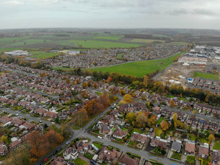 Aerial photo taken above a typical housing estate in the UK showing the tops of the houses on a partly cloudy day.