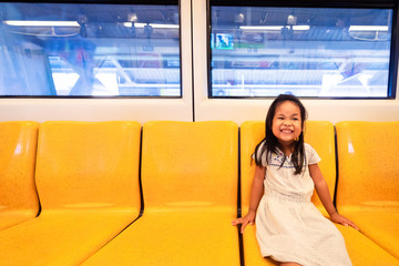 Asian little girl enjoy and fun in bogey of sky train or electric train for travel or transport in city on holiday