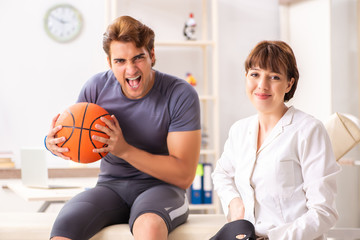 Obraz premium Handsome basketball player visiting female doctor traumatologist