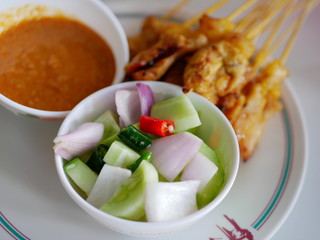 Close up of cucumber relish (Ajad) on a plate being served along with peanut sauce and pork satay