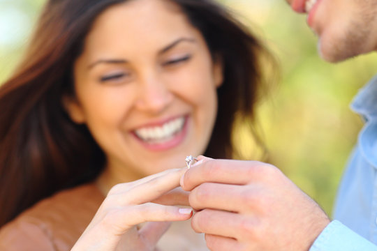 Man putting engagement ring to his glad girlfriend