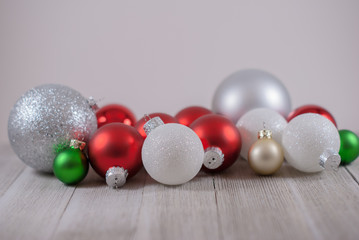 Variety of sizes of red, white, silver, and green Christmas ornaments on white boards with a white background