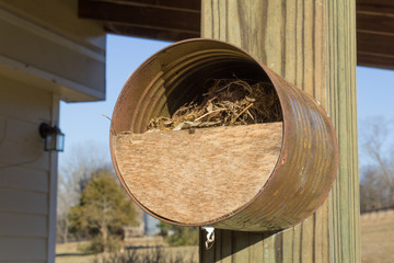 Steel can birdhouse mounted to a wood post, horizontal aspect