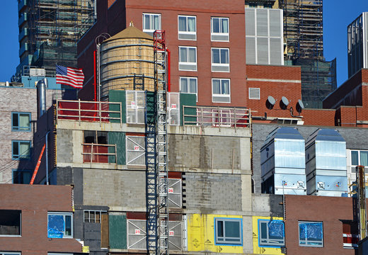 Colorful facade of building exteriors with American Flag and water tower in Manhattan New York City