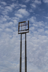 Tall empty highway sign frame against a blue sky with clouds, centered, copy space, vertical aspect