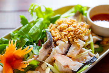 Boiled Asian redtail catfish with original Thai spicy seafood sauce close up.