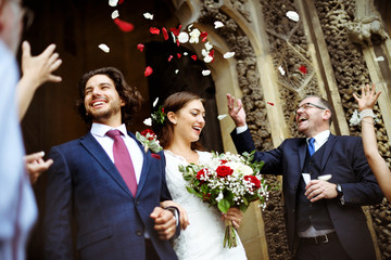 Family throwing rose petals at the newly wed bride and groom