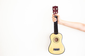 Obraz premium Women's hand holds the classic Ukulele close up with copy space in left side.