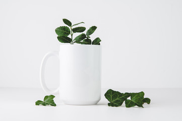 white mug mockup on a white background with greenery