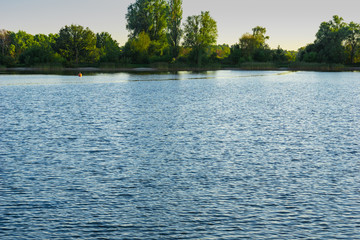 Blue lake with cloudy sky, nature series, a lake landscape with reflection from some trees.