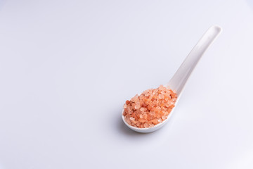 Fototapeta na wymiar Pink himalayan salt on white spoon and on white background - isolated, copy space, soft light