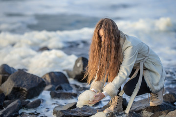 A young girl on the shore of a stormy sea is photographed on a tourist trip around Sakhalin Island walking along the shore admiring nature.