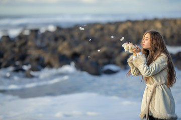 A young girl on the shore of a stormy sea is photographed on a tourist trip around Sakhalin Island walking along the shore admiring nature.