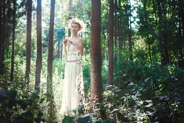 Young model is posing as a fairy in a forest 