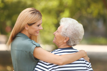 Woman with elderly mother outdoors on sunny day