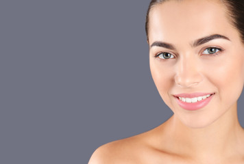 Fototapeta premium Portrait of beautiful young woman and space for text on grey background. Cosmetic surgery concept