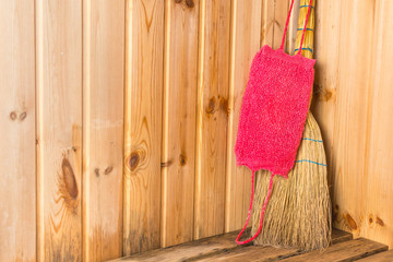Red bast with a yellow broom stand on a shelf in the corner of the bath