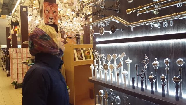 young beautiful girl in kerchief, chooses the store fixtures and window cornices