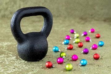 Fototapeta na wymiar Black kettlebell on a green velvet background with colorful ball ornaments, holiday fitness