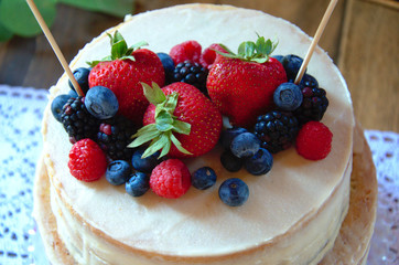 A vanilla wedding cake decorated with strawberries, blueberries, and blackberries
