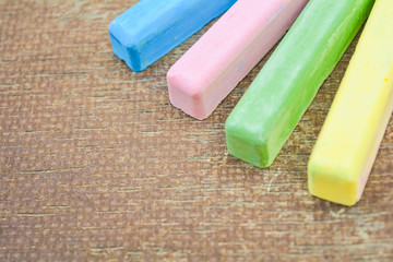 Colored chalk sticks on old wood board as copy space background