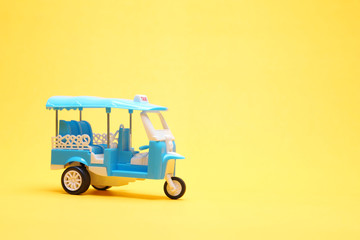 blue tricycle toy or blue auto rickshaw toy on yellow paper background with copy space
