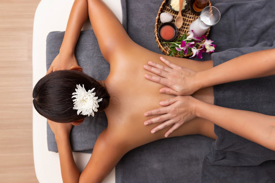 Asian woman enjoying a salt scrub massage at spa.