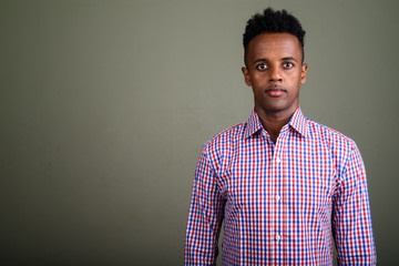 Obraz premium Young handsome African businessman against colored background