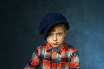 Portrait of a boy in a knitted hat on a dark background