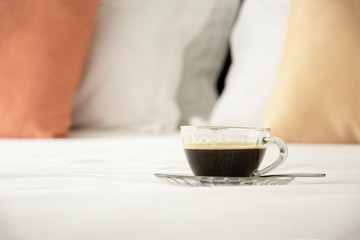 Hot coffee on a white bed, breakfast concept.