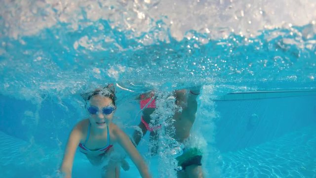 Slow motion shot of three kids jumping into the pool
