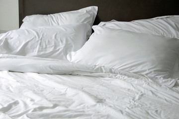 Messy white bed and pillow, in the morning
