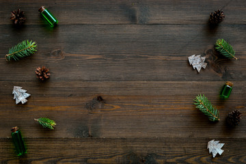 Winter ornament, New Year pattern. Pine sprigs, cones, spruce figure, fir oil on dark wooden background top view copy space