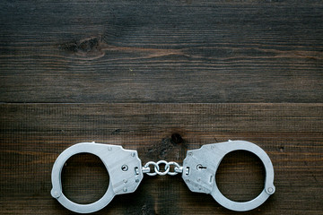 Metal handcuffs on dark wooden background top view copy space