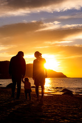 夕陽の沈む海岸と家族のシルエット