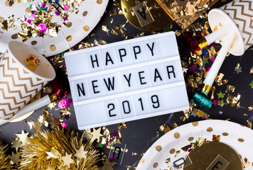 Happy new year 2019 on light box with party cup,party blower,tinsel,confetti.Fun Celebrate holiday party time table top view.