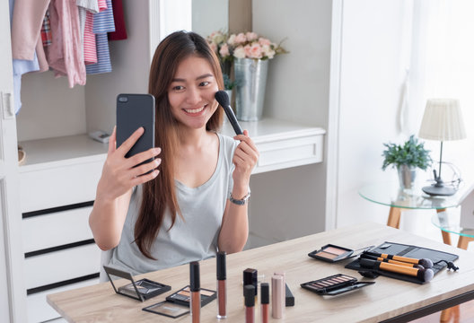 Asian young female blogger recording vlog video use mobile with makeup cosmetic at home online influencer on social media concept.live streaming viral.