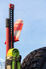 Part of High Lift Jack, Shovel, Winching Rope and Mud Terrain Tyre on blue sky background