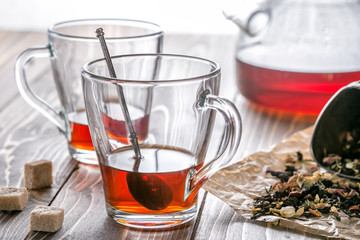 Two glass cup of tea and teapot on wooden surface.