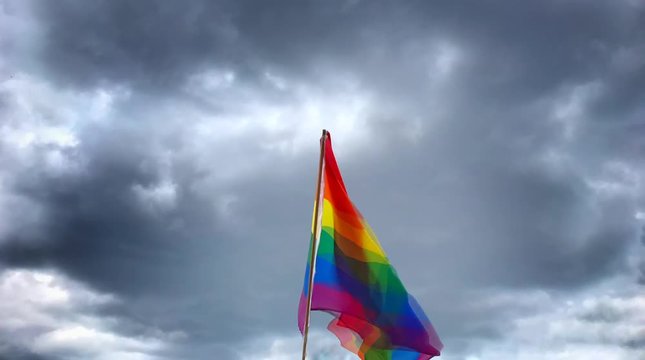 Pride flag stop motion or cinema graphic animation with dark dramatic sky.