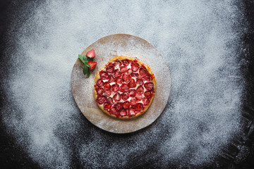 Round cake with strawberries on a thin dough.
