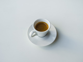 A Cup of strong black coffee on a white table.