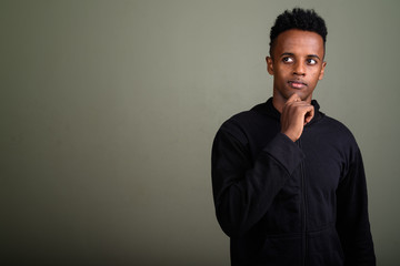 Fototapeta premium Young handsome African man wearing hoodie against colored backgr