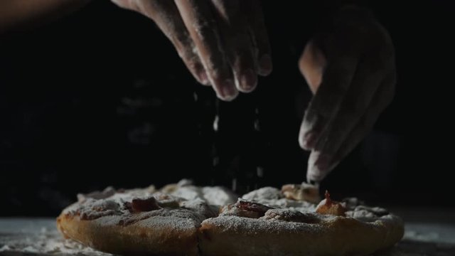 Woman hand sprinkle flour to pizza in slow motion