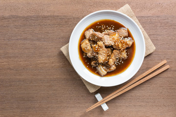 top view of pork belly with teriyaki sauce in a ceramic dish on wooden table. asian homemade style food concept.