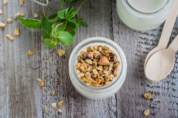 Healthy breakfast. Homemade oat granola with greek yogurt and mint leaves on wooden background. Top view, copy space
