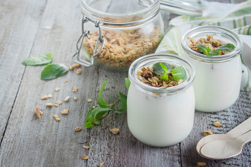 Healthy breakfast. Homemade oat granola with greek yogurt and mint leaves on wooden background. Copy space