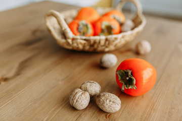 Persimmon fruits and walnuts in a wicker basket. Agriculture and harvesting concept