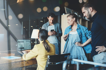 Business office concept. Four employees discuss work tasks and plans and working on laptop